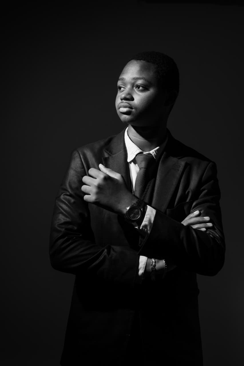 Kevin Zié Yeo en costume, bras croisés, portrait noir et blanc.
